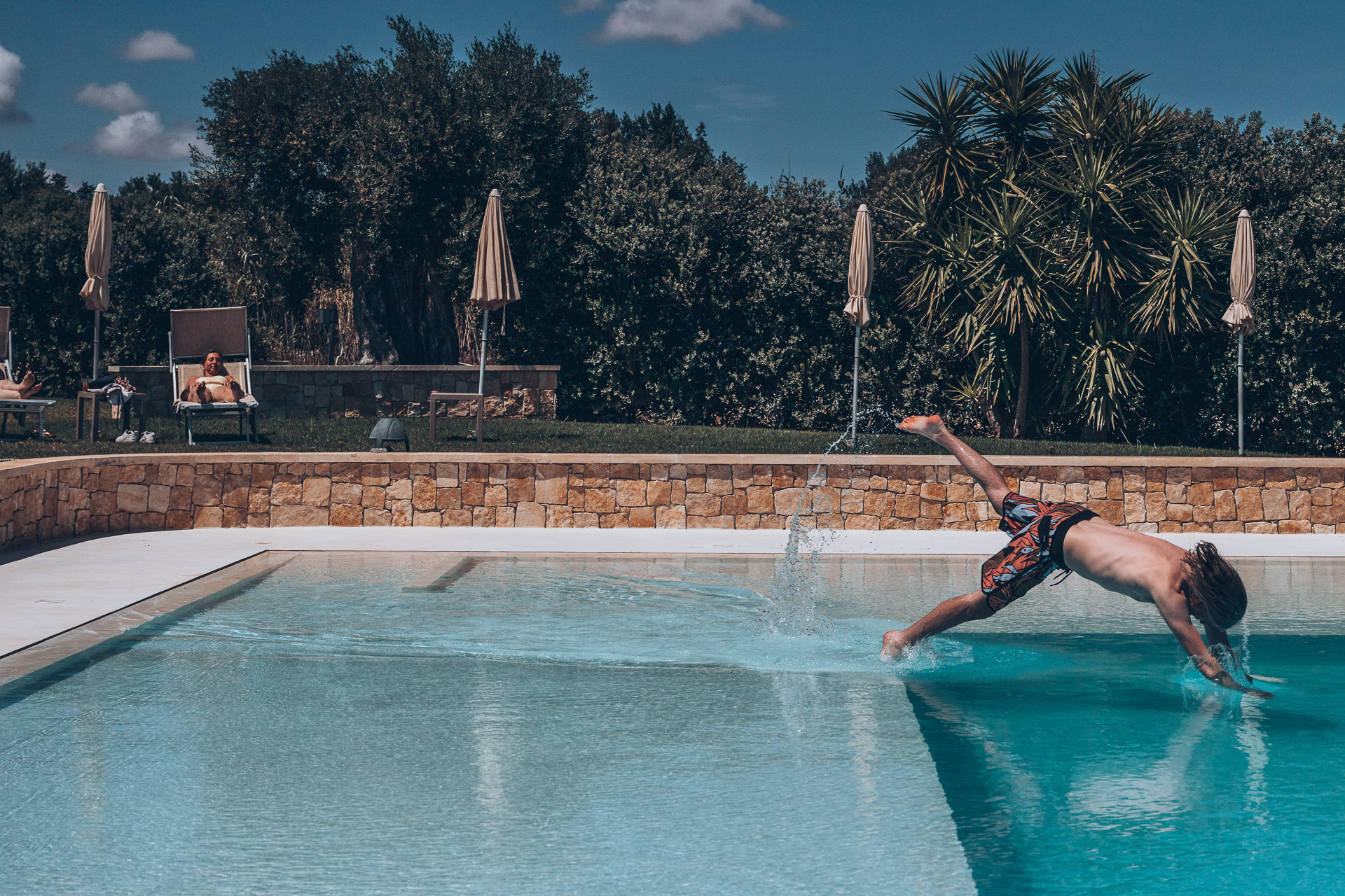 Destination wedding photography - A man jumps into a pool